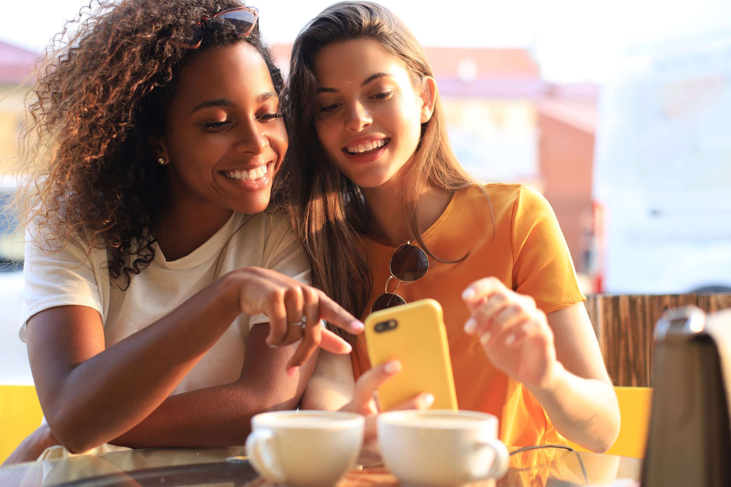 photo of two friends having coffee and shopping local businesses on their phones using local seo.