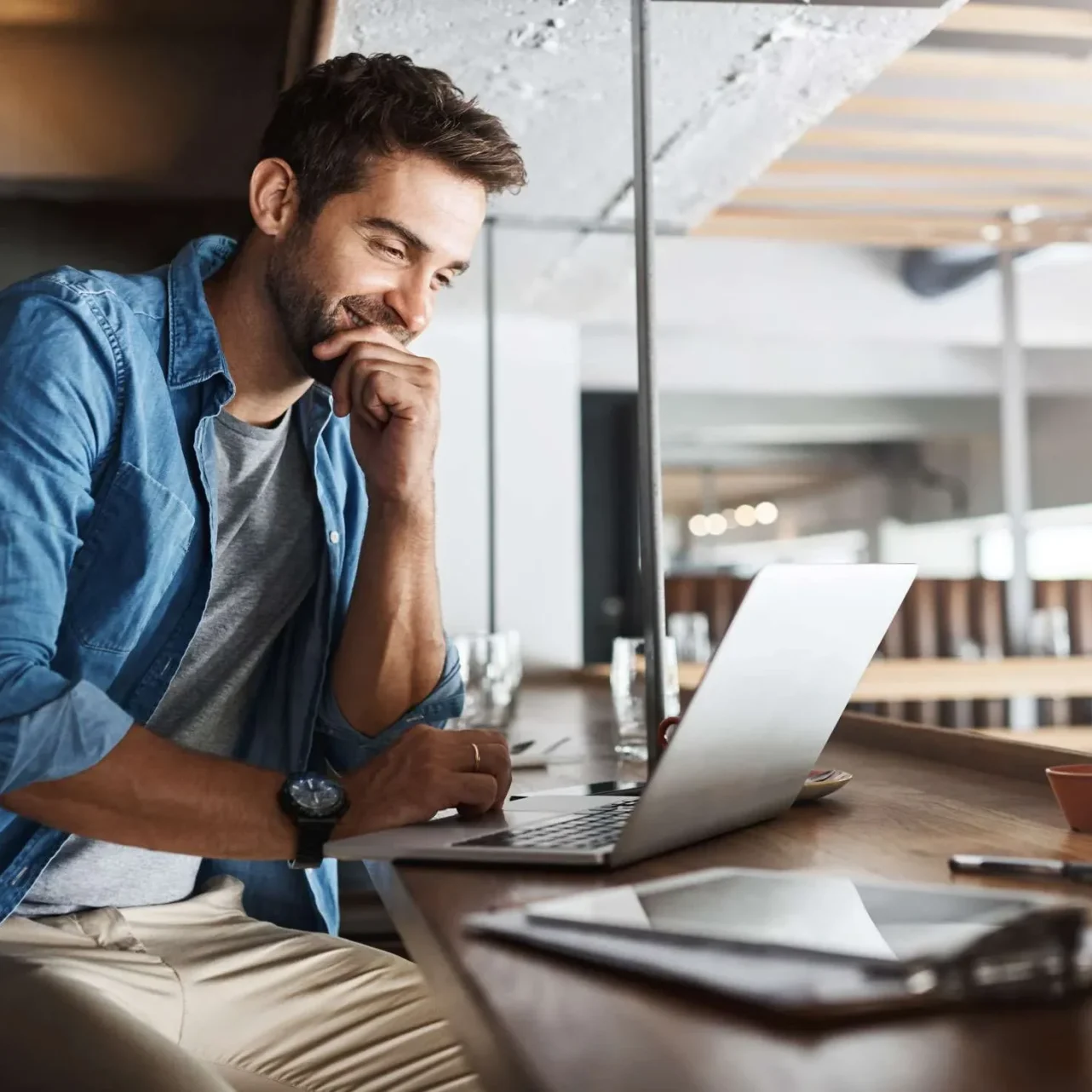 Smiling business owner checking his recovered website on a laptop in a café