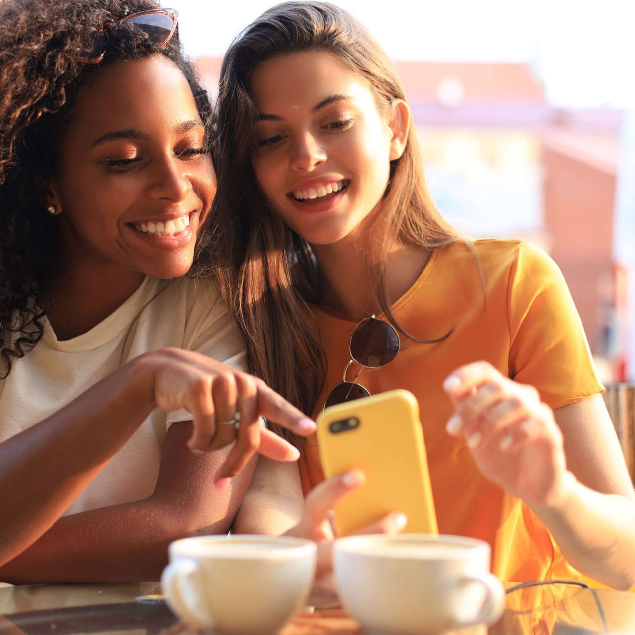 photo of two friends having coffee and shopping local businesses on their phones using local seo.