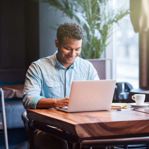 Small business owner smiling while working on a laptop, representing ADA web accessibility compliance for local businesses