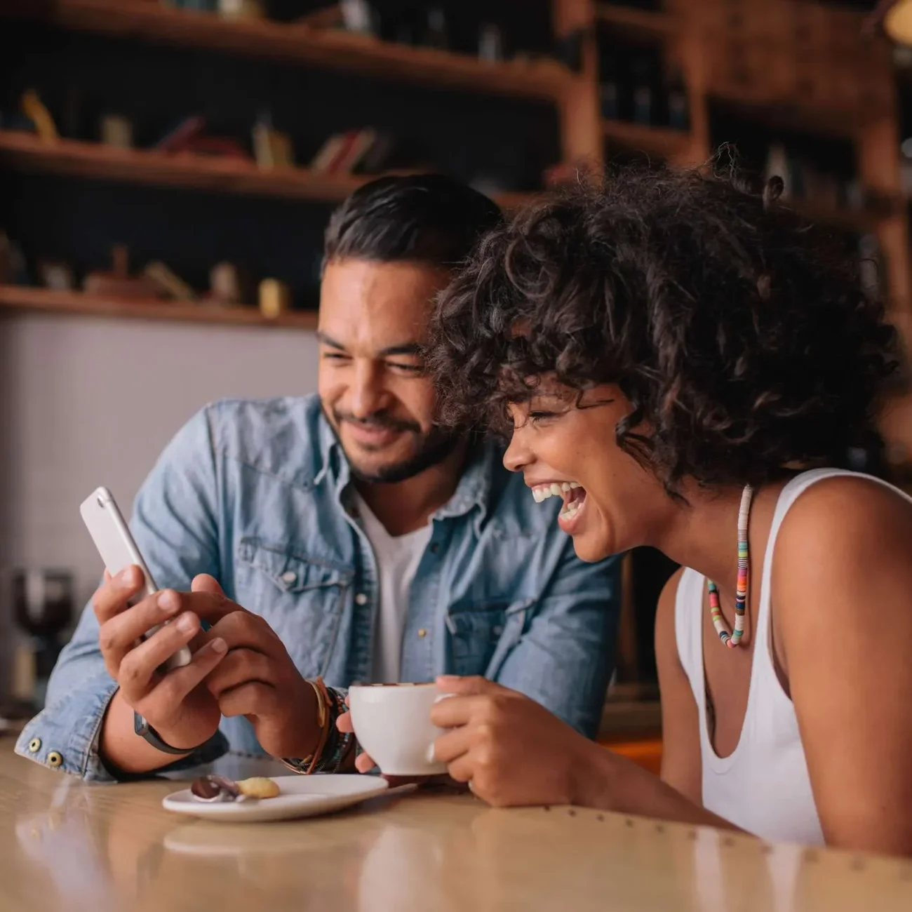 Smiling couple looking at their phone together in a local coffee shop