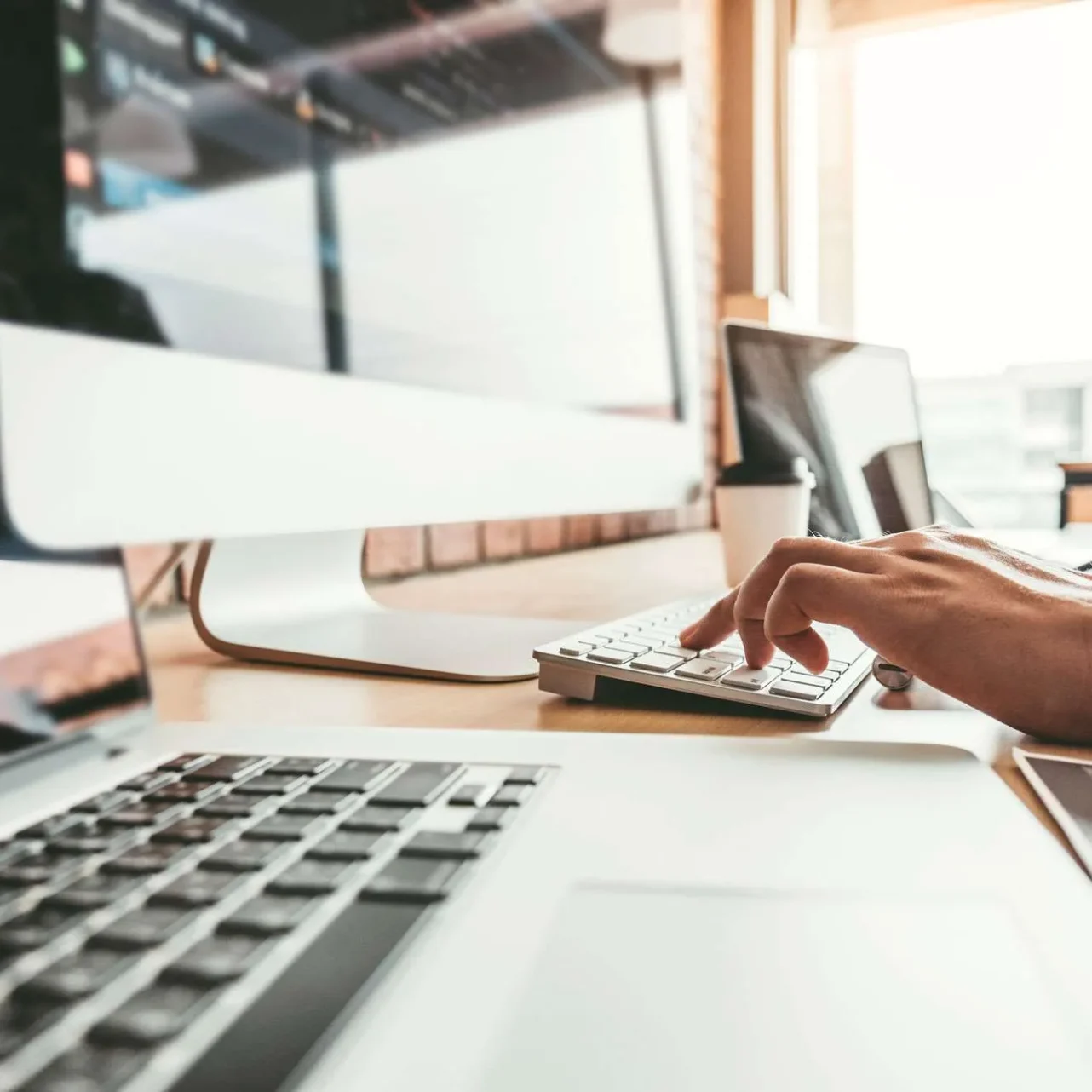 Web developer typing at a desktop and laptop while working on WordPress website repair